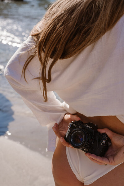 Photographer is sitting on the rocks on Ibiza posing for personal branding photography on Ibiza