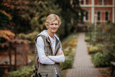 A senior high school boy poses alongside willow grasses for his outdoor senior photography session.