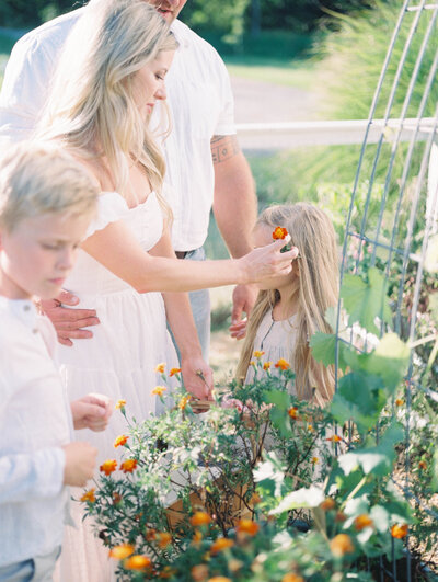 Film image of mom putting flower in little girl's hair in a garden by family photographer Richmond VA
