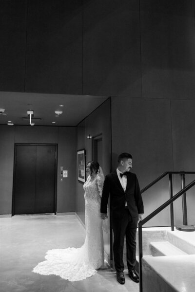 Bride and groom holding hands around a corner for a private moment before their ceremony at Winter Park Events Center in Florida — black and white photo capturing the emotional anticipation of their wedding day.