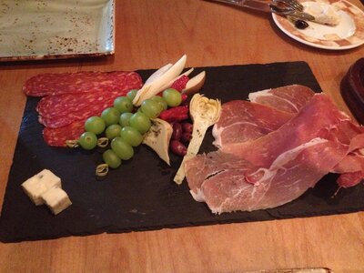 Elegant charcuterie board with cured meats, cheese, grapes, and artichokes on a slate platter — captured during a Miami lifestyle event.
