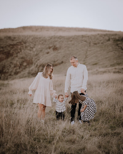 Family holding hands amongst long grass on beach cliffs