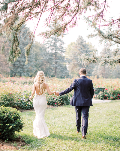 Bride and groom holding hands and walking away in an omaha garden