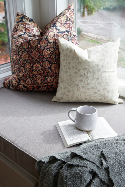 white kitchen counter, white walls, white floating shelf with neutral clay dishware, white bowl with coconuts, wood cutting board, white mugs with hand pouring coffee from french press