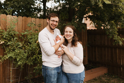 Mother and father with newborn smiling at camera