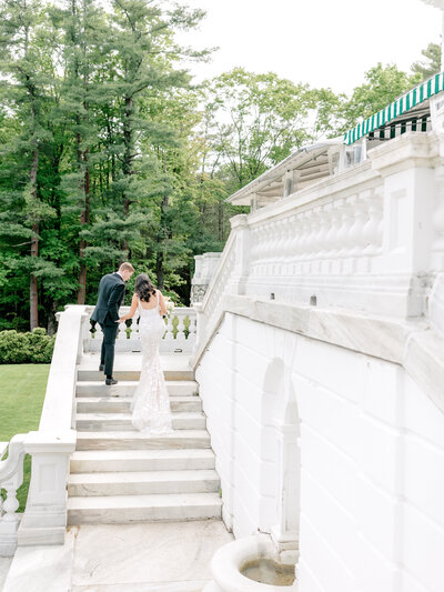 Bride and groom walk up the steps at The Mount, Edith Wharton's Home holding hands