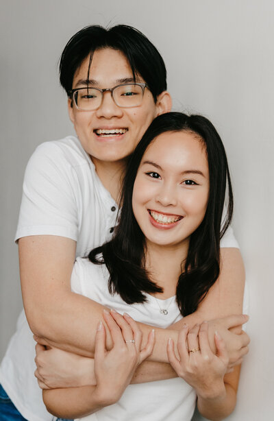 Studio photo of a couple in white tees with their arms around each other