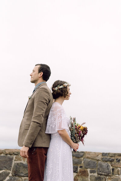 Cinematic wide shot of the couple embracing on the summit, with soft focus and natural light.
