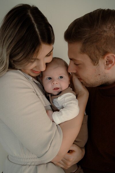 Close up van moeder en vader die tussen hen in hun zoontje liefdevol aankijken.