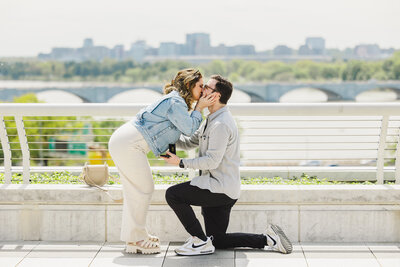 a person kissing their partner who is down on one knee proposing