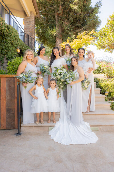 Bride stands with her bridesmaids and flower girls on steps at wolf heights venue in Sacramento, ca.