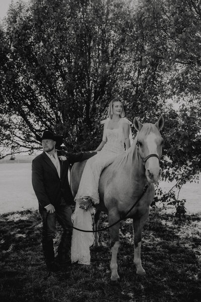 bride sits on horse at their ranch wedding