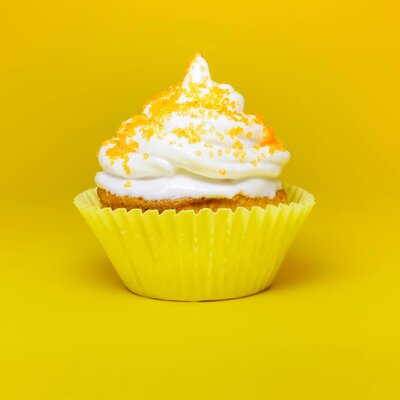 Vanilla cupcake with white frosting and yellow sprinkles in a yellow wrapper