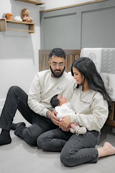 Lifestyle newborn photography session with parents holding baby in front of window with natural light— captured by Alliston and Barrie maternity, newborn, and family photographer.