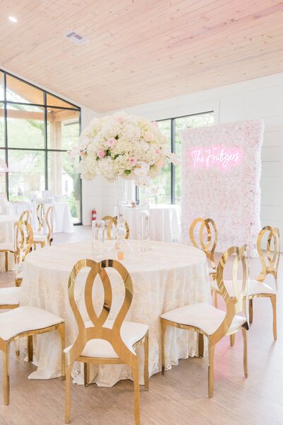 a white table with gold chairs and a pink and white floral centerpiece