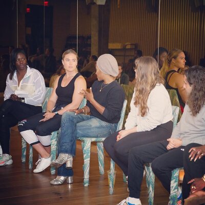 A group of women sitting down at a workshop speaking on mental health as a top performer