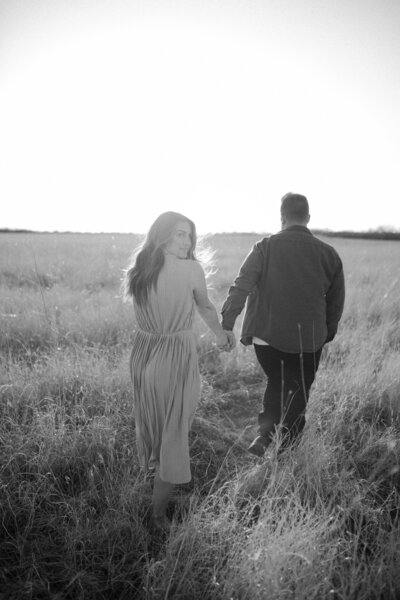 black and white image couple holding hands in field
