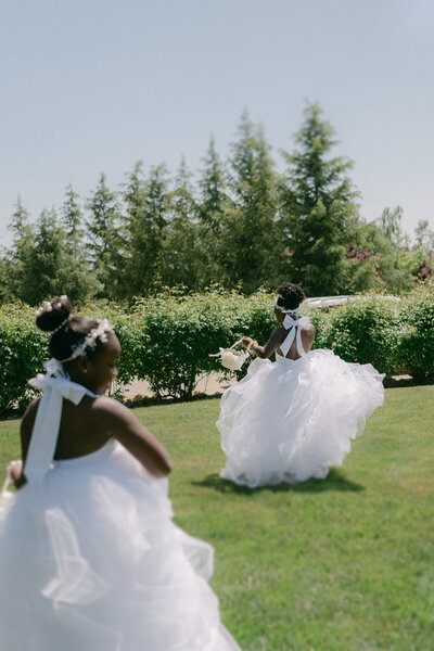 Oahu wedding photographer documents flower girls dancing in field.