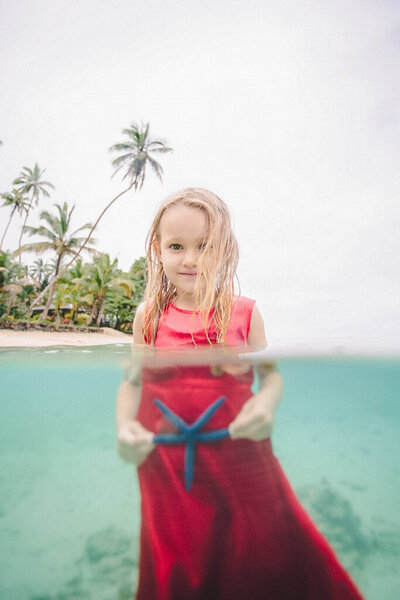 little girl in red dress holding starfish