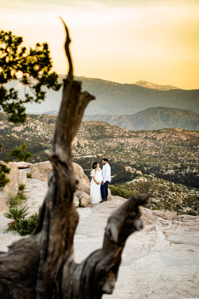 Mount Lemmon maternity photo shoot couple standing on rocks with sunset