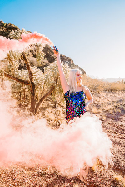 high school senior in sparkly dress holding pink smoke bomb