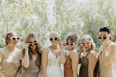 Bride with her bridesmaids with fun heart shaped sunglasses.