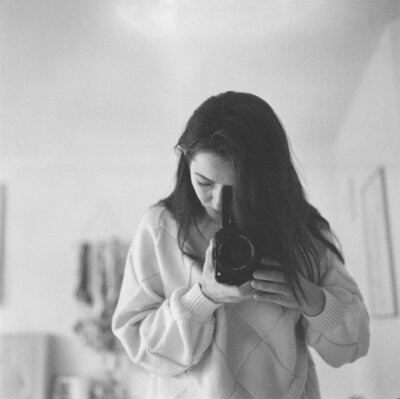 Seattle wedding photographer Brittany carvalho -brunette female photographer holding a contax 645 black medium format camera with a blue dress on
