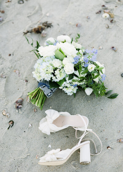 brides bouquet and shoes on the sand at wiano beach club