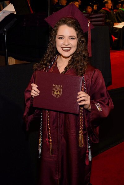 woman holding diploma and smiling at the camera
