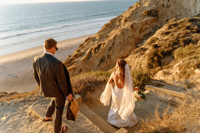 bride and groom walking down cliff