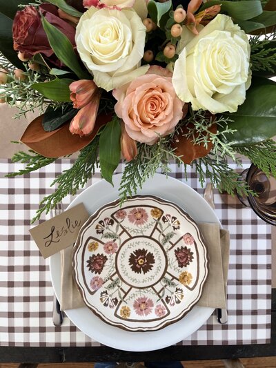 Kraft paper place card with brown brush lettering on thanksgiving fall themed table.
