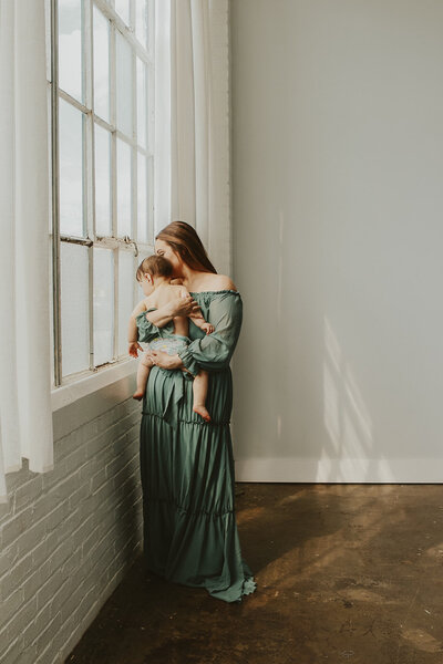 beautiful photo of a mother holding her son, looking out of a pittsburgh photography studio window