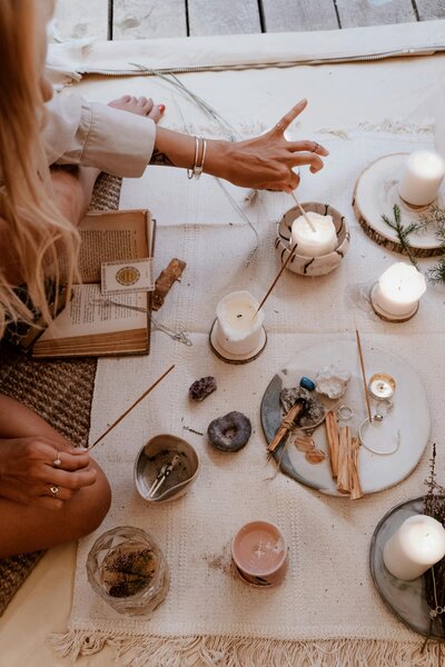 Woman sits in ceremony with candles, a journal, and incense.
