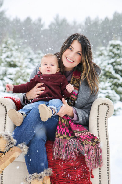 Mom with baby on chair in snow | Family Photo Session