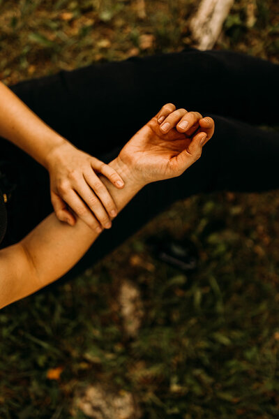A woman touching her own arm, connecting to her physical body.