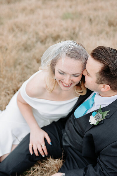 Photo of bride and groom sitting in a field in Texas.
