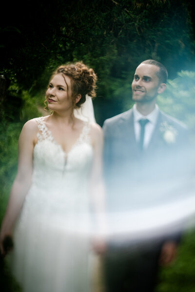 A couple looking to their right whilst holding hands during their wedding at Arnos Vale in Bristol. Free lensing technique used.