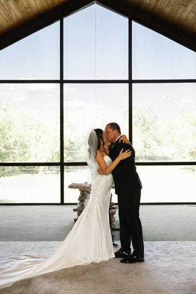 Bride and groom posing elegantly inside their wedding venue, surrounded by beautiful decor, captured in a timeless and romantic portrait.