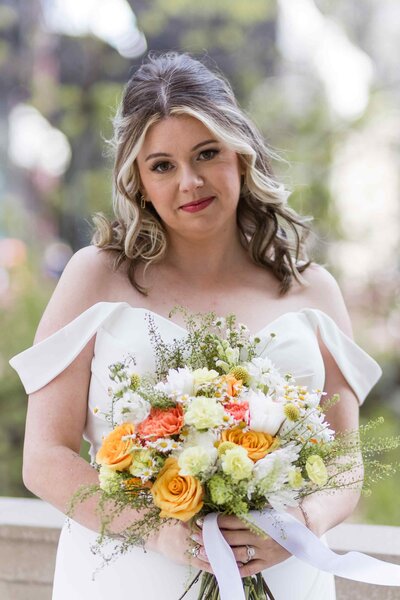 Bride smiles holding colorful bouquet