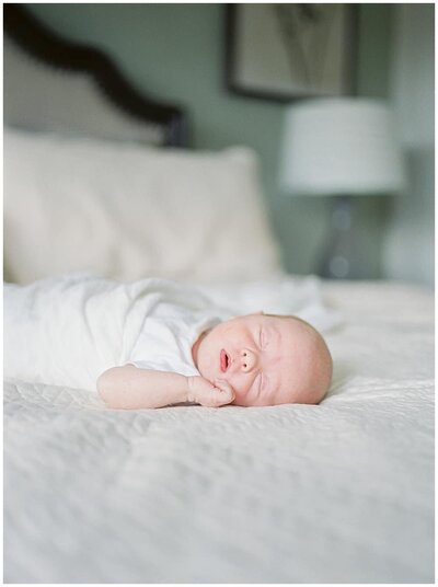 A newborn baby peacefully sleeping on a white bed during a Northern Virginia Newborn Photography Session