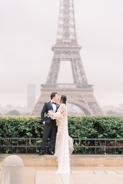 Rainy days in Paris, bride and groom kiss in front of the Eiffel tower