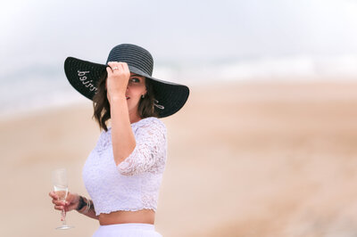 bride on the beach holding hat