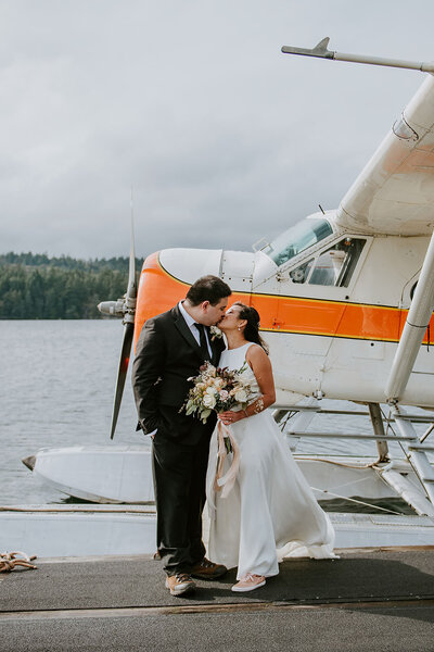 Couple kissing in front of their Sunshine Coast Air float plane about to head on their beautiful adventure elopement with Coastal Weddings and Events at Chatterbox Falls B.C