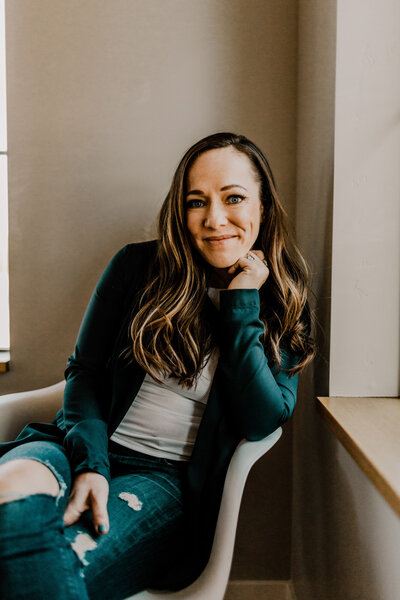 Season sitting in a chair with her legs crossed smiling