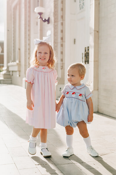 Two young sisters holding hands and running together during their family session.