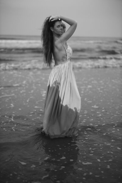woman on a beach in a dress holding up her hair