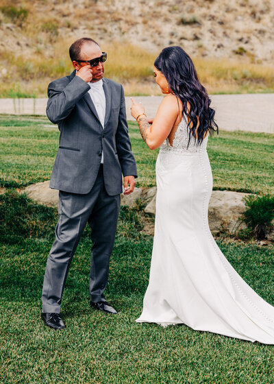 Father wiping tears during first look with daughter bride