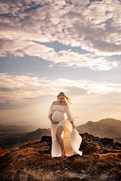 Pregnant woman standing gracefully atop Te Mata Peak at sunset, Hawke's Bay – breathtaking maternity photography by a local Hawke's Bay photographer, capturing the golden glow over the Heretaunga Plains, ideal for expectant mothers seeking stunning outdoor sessions in Napier, Hastings, and Havelock North
