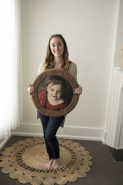Ashley holding a round wall art piece she created.