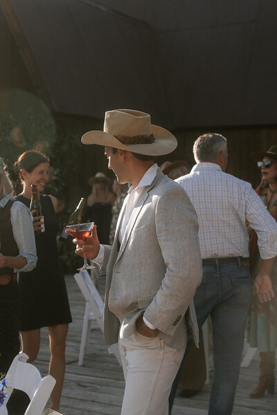 Wedding guest dressed in western attire holding signature cocktail